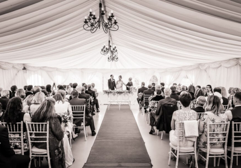 Guests gather for a wedding ceremony in a beautifully decorated marquee at Fernhill House Hotel.