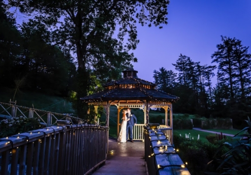 A couple embracing under a lit gazebo at twilight in Fernhill House Hotel gardens.