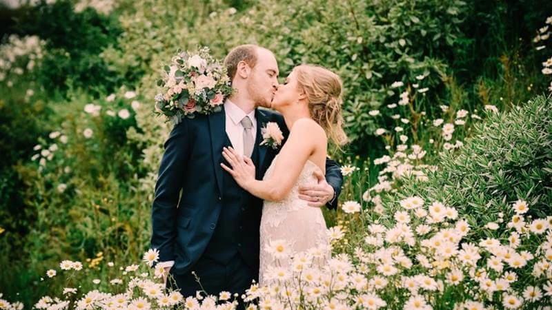 Couple kisses in a flower-filled garden at Fernhill House Hotel.