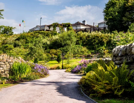 A couple strolls a garden path at Fernhill House Hotel, surrounded by lush greenery.