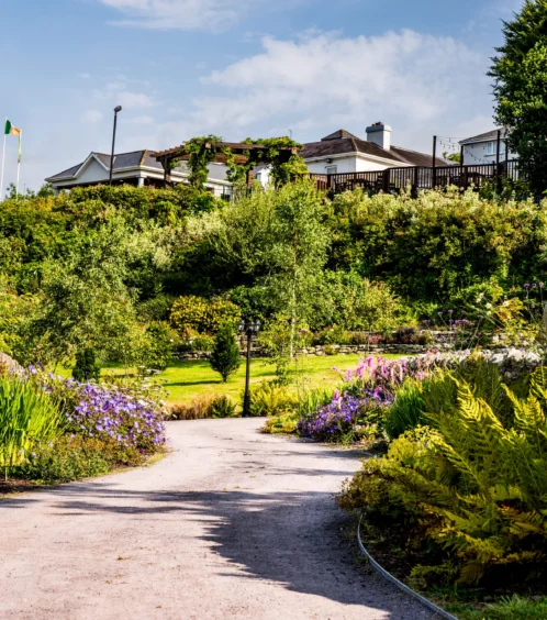 A couple strolls a garden path at Fernhill House Hotel, surrounded by lush greenery.