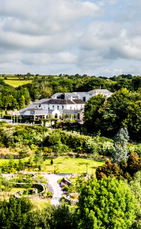 Aerial view of Fernhill House Hotel in lush green countryside, surrounded by gardens and trees.
