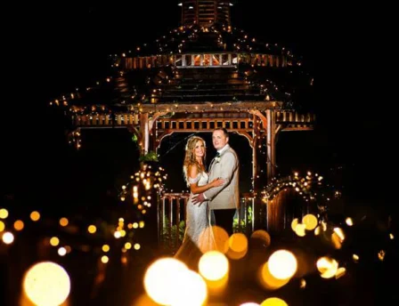 Couple embraces under fairy-lit gazebo at Fernhill House Hotel garden.