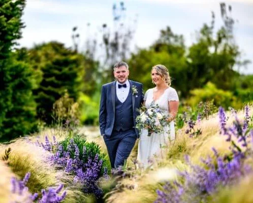 Couple walking through lush garden at Fernhill House Hotel.