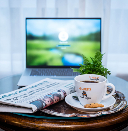 Cosy hotel seating area with coffee, newspaper, and laptop.