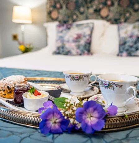 Cosy hotel room with tea and scones on a tray, inviting atmosphere.