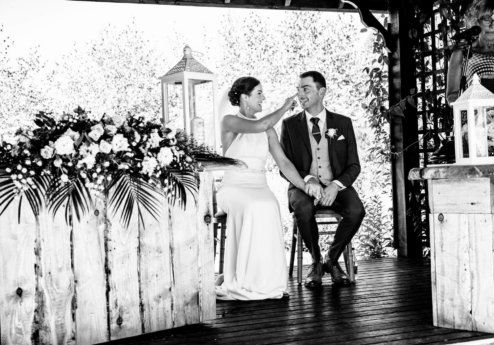 A couple smiling during their wedding ceremony at Fernhill House Hotel's charming outdoor venue.