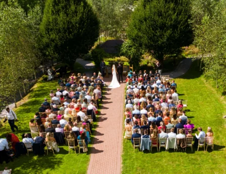 A couple weds in a serene garden setting at Fernhill House Hotel, surrounded by guests.