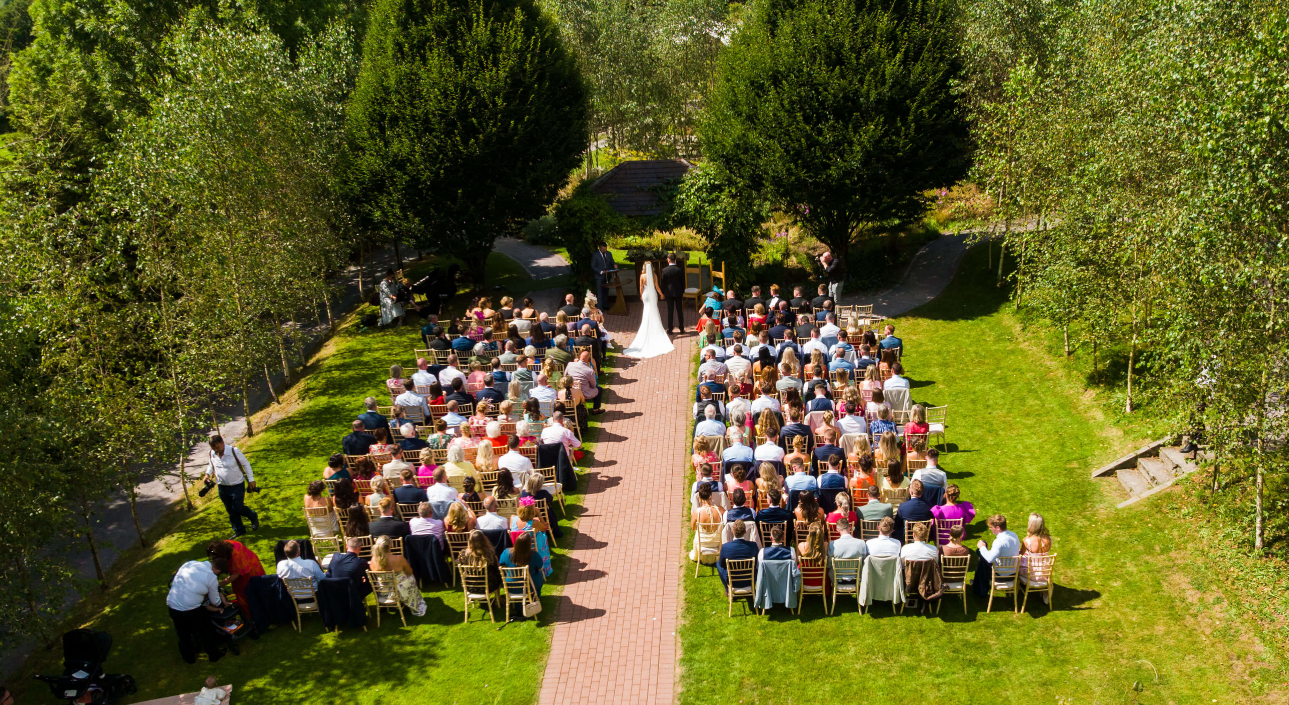 Outdoor wedding ceremony with guests seated on a lush green lawn at Fernhill House Hotel.