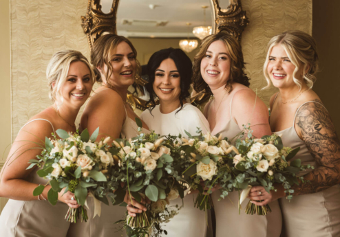 A joyful bride with bridesmaids holding bouquets in Fernhill House Hotel.