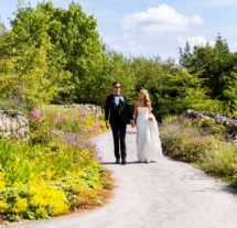 Couple walking hand in hand through a lush garden path in Fernhill House Hotel grounds.