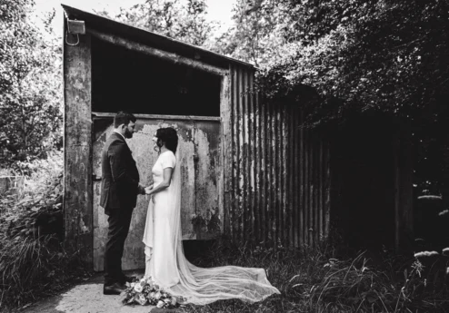 Couple holding hands near rustic building at Fernhill House Hotel garden.