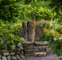Peaceful garden scene at Fernhill House Hotel, featuring lush greenery and a stone bench.
