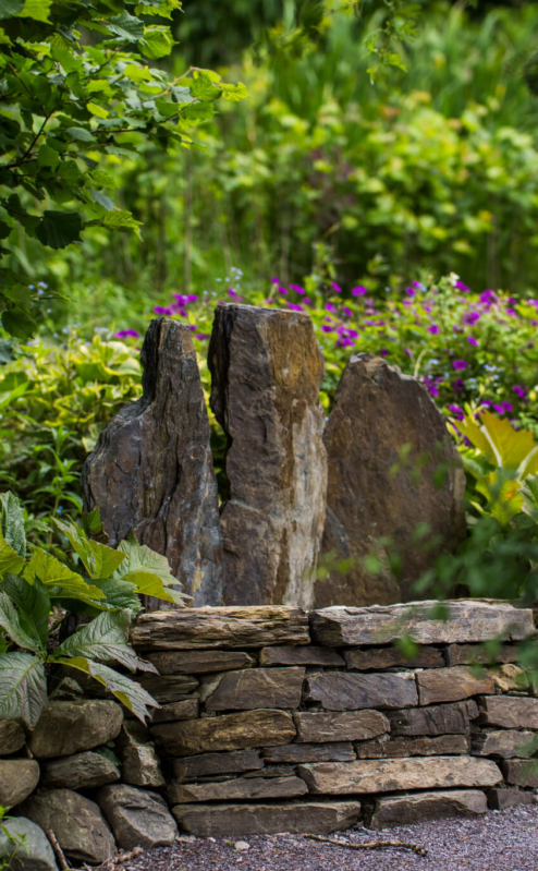 Peaceful garden scene at Fernhill House Hotel, featuring lush greenery and a stone bench.