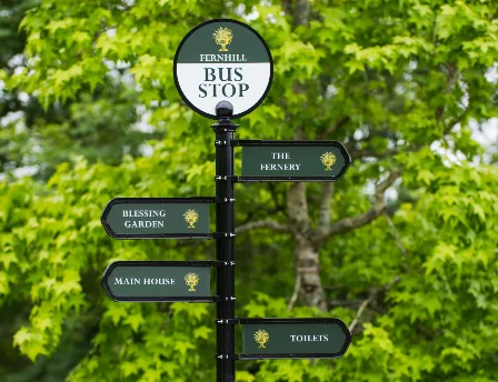 Signpost in lush Fernhill House Hotel garden with directions to amenities.