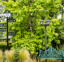 Lush garden with ornate bench and directional signs at Fernhill House Hotel.