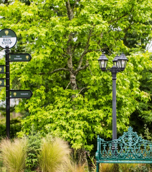 Family garden area at Fernhill House Hotel with seating and directional signs.