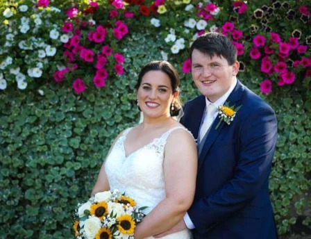 Smiling couple in garden with vibrant flower backdrop at Fernhill House Hotel.