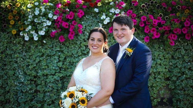 Smiling couple in garden with vibrant flower backdrop at Fernhill House Hotel.