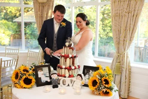 A couple cutting a wedding cake surrounded by sunflowers at Fernhill House Hotel.