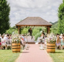 Couple exchanging vows in a picturesque garden with family gathered.