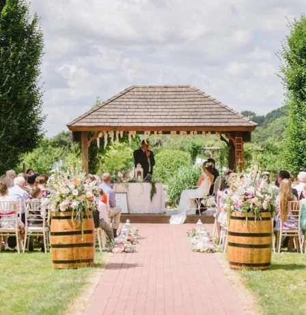 Couple exchanging vows in a picturesque garden with family gathered.