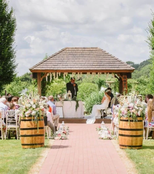Couple exchanging vows in a picturesque garden with family gathered.