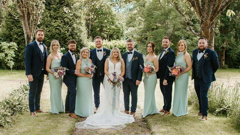 A wedding party poses in an elegant garden at Fernhill House Hotel.