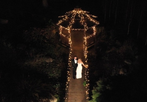 A couple walks towards a gazebo lit with fairy lights at night in Fernhill House Hotel's garden.