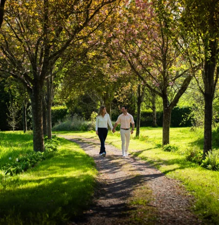 Couple strolling on a tree-lined path in Fernhill House's lush garden.