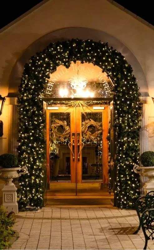 Family entering Fernhill House Hotel adorned with festive lights and greenery.