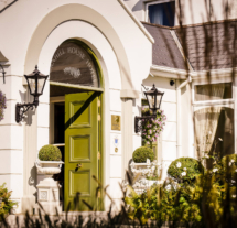 Warm entrance of Fernhill House Hotel with open green door and welcoming floral decor.