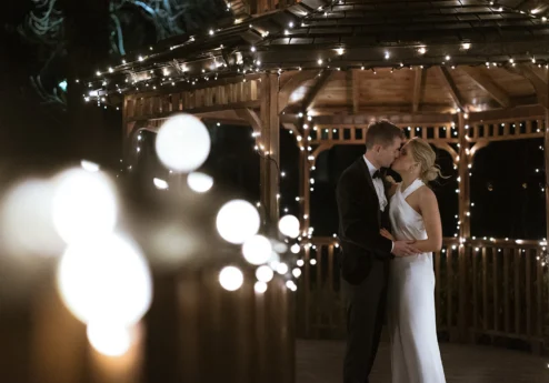 A couple kissing under fairy-lit gazebo at Fernhill House Hotel.