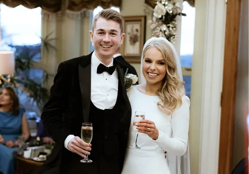 A joyful couple dressed elegantly, celebrating with drinks at Fernhill House Hotel.