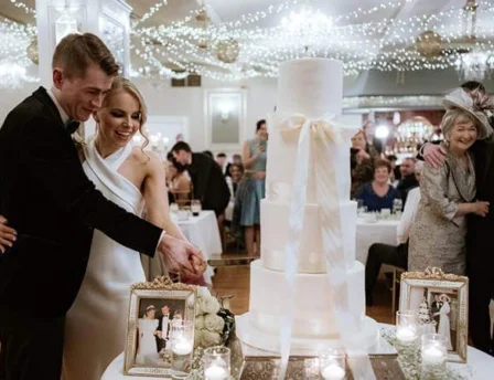 Elegant wedding celebration with couple cutting cake under twinkling fairy lights in Fernhill House.