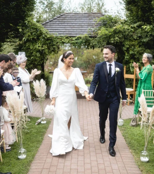 A couple celebrates their wedding outdoors at Fernhill House Hotel, surrounded by cheering family.