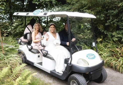 Couple enjoying a ride in a golf cart surrounded by lush greenery at Fernhill House Hotel.