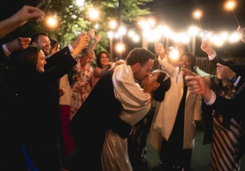 Couple kissing under sparklers at evening celebration with friends.