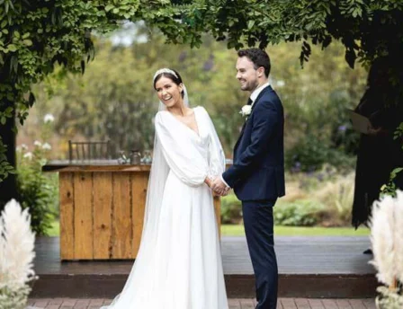 A couple joyfully stands in a lush garden at Fernhill House Hotel, exchanging vows.