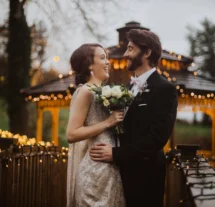 A couple embraces on a bridge decorated with fairy lights at Fernhill House Hotel.