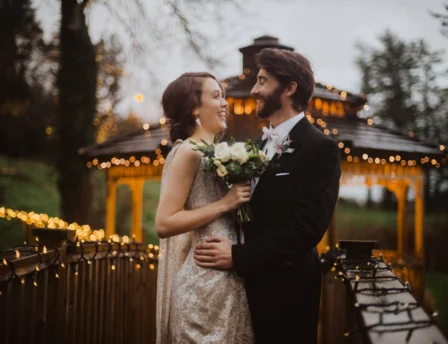 A couple embraces on a bridge decorated with fairy lights at Fernhill House Hotel.