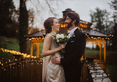 A couple embracing on a decorated bridge at Fernhill House Hotel.