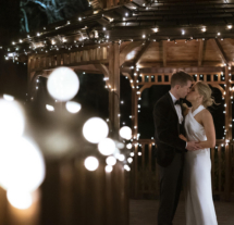 A couple kisses under a fairy-lit gazebo at Fernhill House Hotel, creating a romantic evening atmosphere.