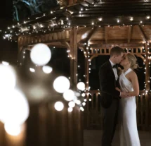 Couple sharing a romantic moment under a gazebo with fairy lights at Fernhill House Hotel.