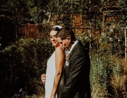 A couple embraces in a lush garden at Fernhill House Hotel.