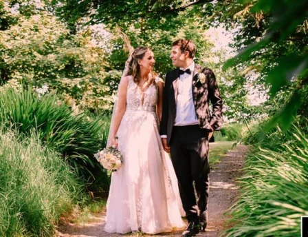 Couple walking through lush garden path, smiling on a sunny day at Fernhill House Hotel.