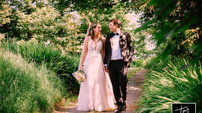 A couple walks hand in hand in a lush garden at Fernhill House Hotel.