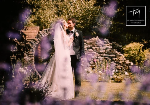 A couple shares a romantic moment in a lush garden at Fernhill House Hotel.