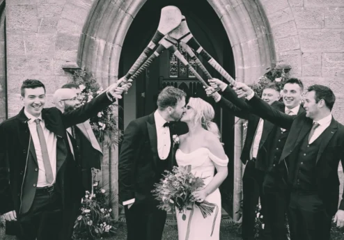 A joyful couple kissing under a hurley arch at Fernhill House Hotel.