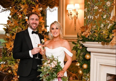 A couple celebrates with champagne by a decorated Christmas tree at Fernhill House Hotel.